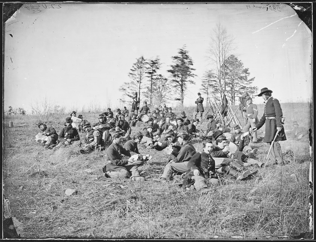 Union soldiers read letters and newspapers, talk, and play cards after drill near Petersburg, Virginia, in 1864.